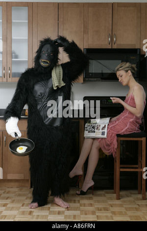 L'homme en costume de gorille les tâches domestiques tout en femme se détend Banque D'Images