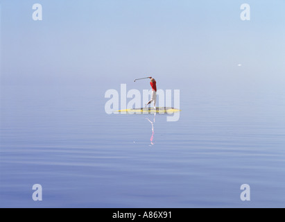 Woman golfer hitting ball off petite île dans l'archipel de Stockholm Banque D'Images