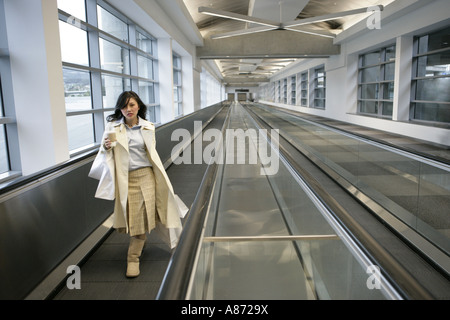 Une jeune femme marche sur la courroie du convoyeur. Banque D'Images