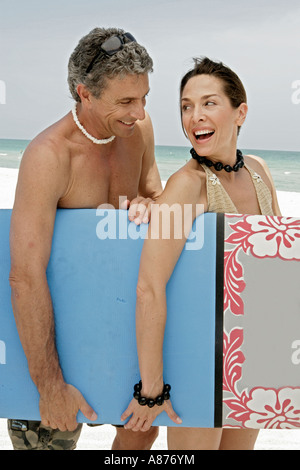 Un couple carrying surfboard on beach. Banque D'Images