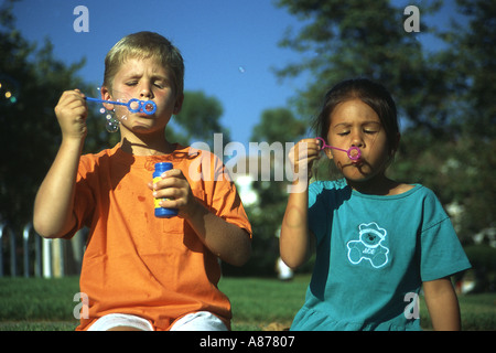 Young Caucasian boy girl Filipina Enfants 6-7 ans ans enfant enfants personne personnes outdoors blowing bubbles multi variée racialement mixtes Banque D'Images