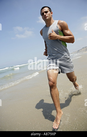 Un jeune homme s'exécute sur une plage. Banque D'Images