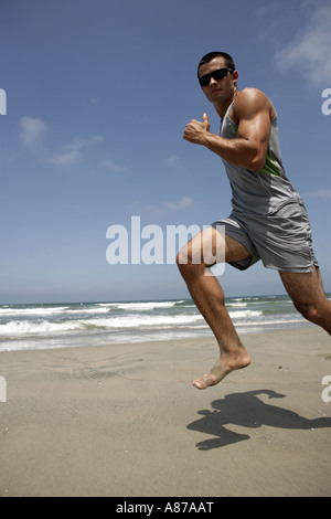 Un jeune homme s'exécute sur une plage. Banque D'Images