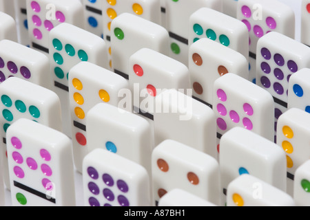 Rangées uniformes de dominos blancs avec des points aux couleurs vives debout sur l'extrémité Banque D'Images