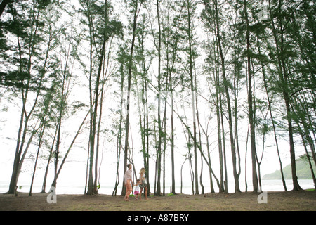 Les femmes avec enfant fille marcher le long des arbres Banque D'Images