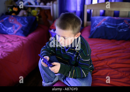 Garçon jouant un jeu garçon jouets électroniques dans la chambre Banque D'Images