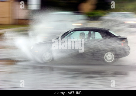 Voiture roulant à travers des routes inondées Banque D'Images
