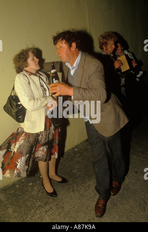 Homme ivre dominant la femme, buvant une bouteille de bière. Festival annuel de jumelage Lisdoonvarna County Clare. Côte Ouest Irlande années 1990 HOMER SYKES Banque D'Images