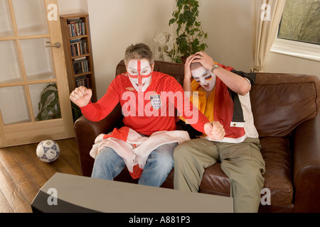 Parution du modèle. L'Angleterre et l'Allemagne de football fans regarder match à la télévision que l'Angleterre gagne et perd de l'Allemagne. Banque D'Images