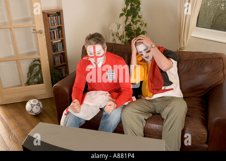 Parution du modèle. L'Angleterre et l'Allemagne de football fans regarder match à la télévision que l'Angleterre gagne et perd de l'Allemagne. Banque D'Images