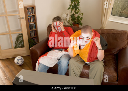 Modèle libéré. Les supporters de football anglais et allemand regardent le match à la télévision alors que l'Allemagne gagne et que l'Angleterre perd Banque D'Images