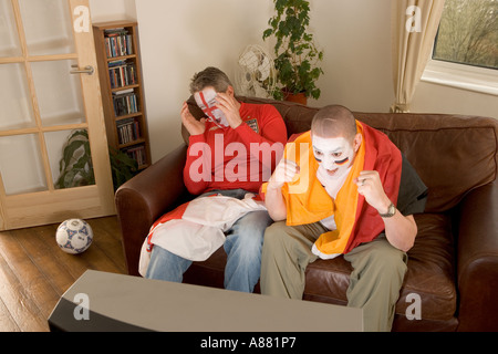 Modèle libéré. Les supporters de football anglais et allemand regardent le match à la télévision alors que l'Allemagne gagne et que l'Angleterre perd Banque D'Images