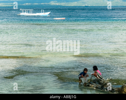 Les jeunes enfants de chercher des coquillages dans les eaux claires de Gili Trawangan, Indonésie. Banque D'Images