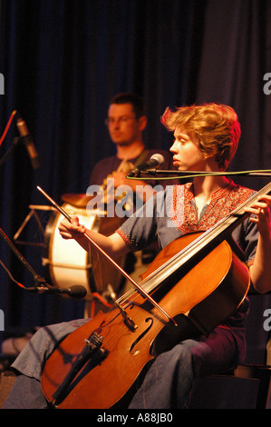 Warsaw Village Band se produisant en concert, mettant en vedette une jeune femme jouant du violoncelle sur scène avec un batteur en arrière-plan. Banque D'Images