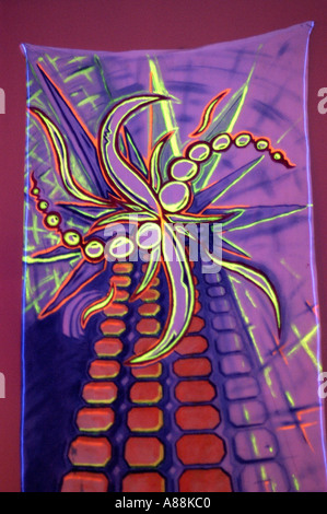Peintures murales trance psychédéliques vibrantes présentant des formes abstraites néon et des motifs géométriques sur un fond de tissu violet. Banque D'Images
