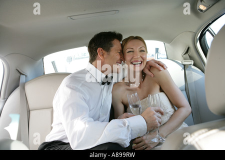 Mature couple laughing dans la banquette arrière d'une voiture Banque D'Images