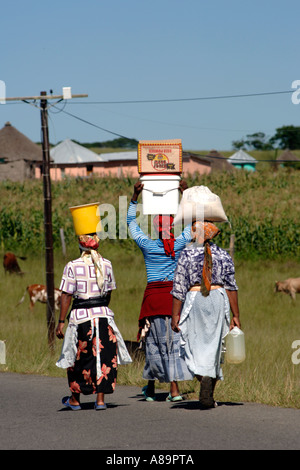 Les femmes Xhosa portant de l'eau dans des seaux et des marchandises dans des boîtes sur leurs têtes dans la province d'Eastern Cape d'Afrique du Sud. Banque D'Images