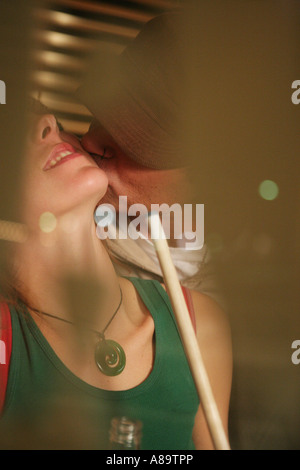 Homme portant une casquette embrassant une femme tenant une queue Banque D'Images