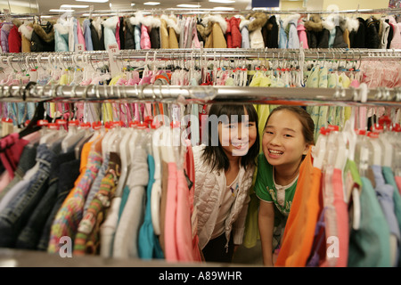 Deux filles asiatiques entre un rack de vêtements Banque D'Images