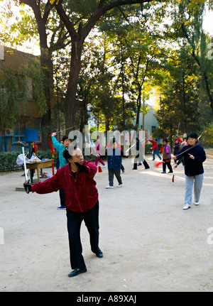 BEIJING CHINE Personnes âgées femmes chinoises et les hommes à l'aide d'épées dans le tai chi au lever du soleil dans un parc du quartier de rester flexi Banque D'Images