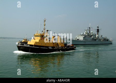 Remorqueur navire exploité par Serco Denholm Bustler A225 en cours d'escorter le navire de la Royal Navy HMS Gloucester à Portsmouth Banque D'Images