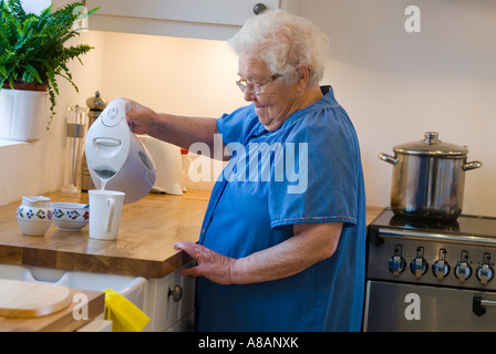 Dame âgée indépendant de prendre une tasse de thé dans sa collectivité moderne cuisine maison Banque D'Images