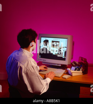 Homme à l'ordinateur regardant dans le passé sur son ordinateur personnel de bureau dans les années 1990 retour dans le temps. Banque D'Images