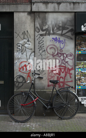 Une image urbaine d'un vélo traditionnel contre un mur et couverte graffitis porte à Amsterdam, l'Europe Banque D'Images