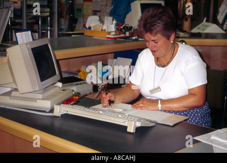 De Travail bibliothécaire sur ordinateur dans Library Numérisation livres Banque D'Images