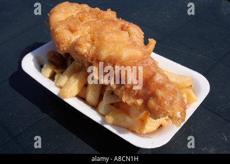 Fish and chips dans un bac en polystyrène sur fond de table en plastique vert Banque D'Images