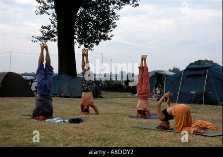 UK festival Womad Reading campeurs faisant du yoga handstands le matin Banque D'Images