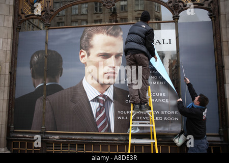 Les hommes de l'affiche accrocher un couvrant sur une fenêtre au Savoy Taylors Guild dans le Strand, London UK. Banque D'Images