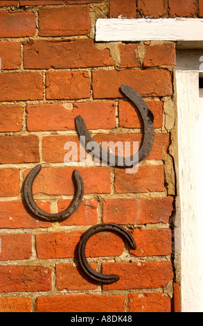 Trois HORSEHOES MONTÉ SUR UN MUR DE BRIQUE ROUGE D'UNE MAISON UK 2005 Banque D'Images