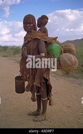 Turmi tribu Hamar femme avec bébé et récipient de l'eau d'argent sur le dos de la région de la rivière Omo Ethiopie Banque D'Images