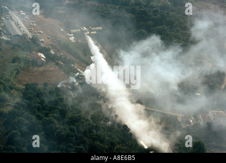 Vue aérienne d'un avion Bombardier d'eau Canadair feu arrosant de l'eau sur un incendie de forêt menace Maisons et voitures, Provence, France, Europe, Banque D'Images
