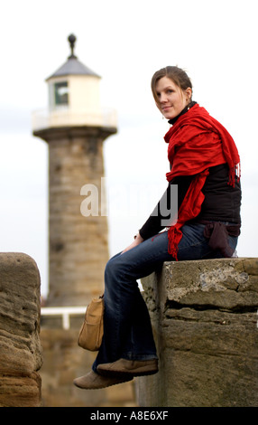 Une femme sur la digue près du phare à Whitby, North Yorkshire Banque D'Images
