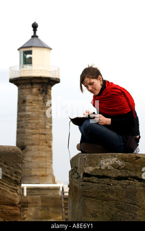 Une femmes écrit sur la digue près du phare à Whitby, North Yorkshire Banque D'Images