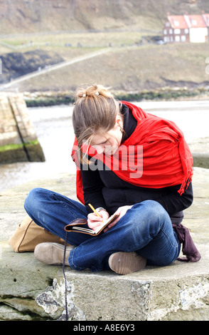 Une femmes écrit sur la digue à Whitby, North Yorkshire Banque D'Images