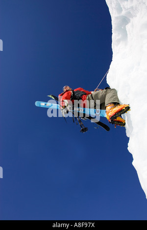 Grimpeur sur glace masculin de glace escalade face avec les skis en sac à dos Banque D'Images