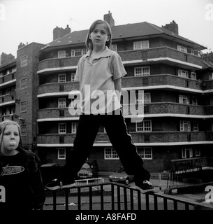 Une jeune fille se tient sur les grilles entourant son conseil housing estate, Clapton, Londres, Royaume-Uni. Banque D'Images