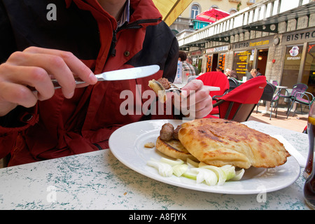 Homme mange la viande hachée cevapcici roll alimentaire nationale populaire dans un petit restaurant à Dolac marché libre Zagreb Croatie Banque D'Images