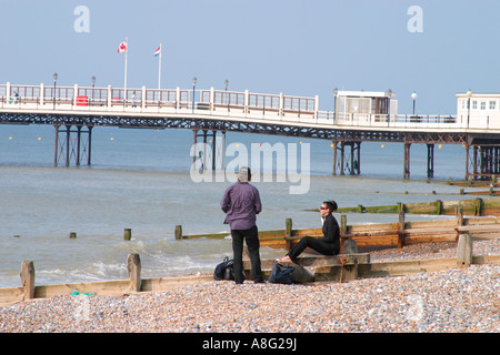 Jeune homme et femme sur la plage de galets près de la jetée de Worthing, West Sussex, Royaume-Uni Banque D'Images