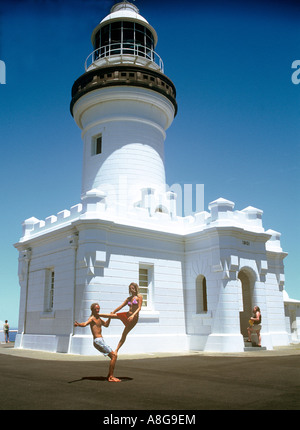 Jeune couple en équilibre sur l'autre en face de Byron Bay Lighthouse, à Byron Bay, New South Wales, Australie Banque D'Images