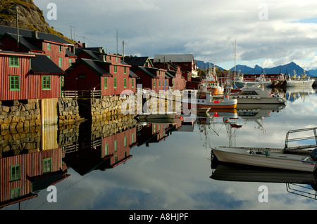 Maisons en bois peintes en rouge dans l'eau miroir Vestvagoya Stamsund Lofoten en Norvège Banque D'Images