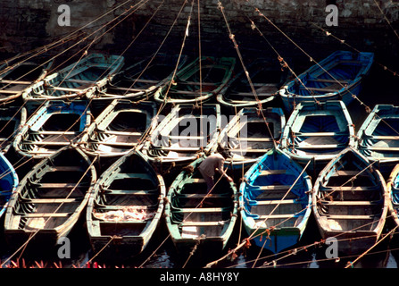 Homme fixant la conduite de chaloupes tous dans une rangée, Essaouira, Maroc Banque D'Images