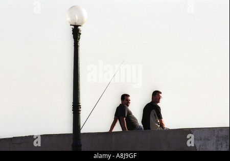 Deux hommes assis sur la requête au port de pêche de la Madrague à l'extérieur Alger en Algérie 2000 Banque D'Images