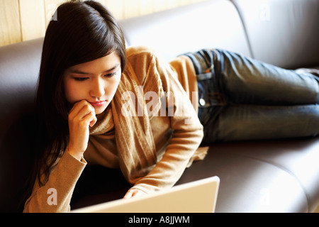 Close-up of a young woman lying on a table en face d'un ordinateur portable Banque D'Images