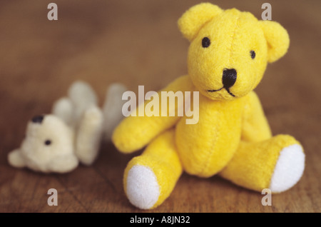 Petit ours jaune assis sur un siège en bois ou à la table au spectateur avec une plus petite plus pâle ted amarré le long Banque D'Images