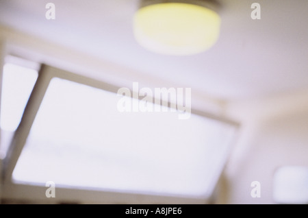 La lumière électrique de flou artistique avec bol en verre lumineux diffuseur de plafond à côté d'un haut niveau fenêtre ouverte sur le mur de la lumière du jour Banque D'Images