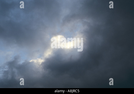 Cumulus blanc englouti par ou en les détachant de cumulus noir en fin d'après-midi avec ciel bleu Banque D'Images